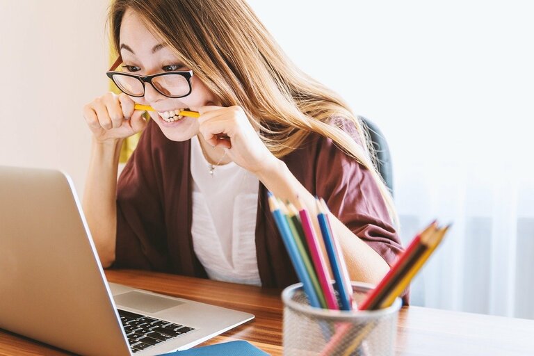 Eine Frau am Laptop beisst getsresst auf ihren Stift